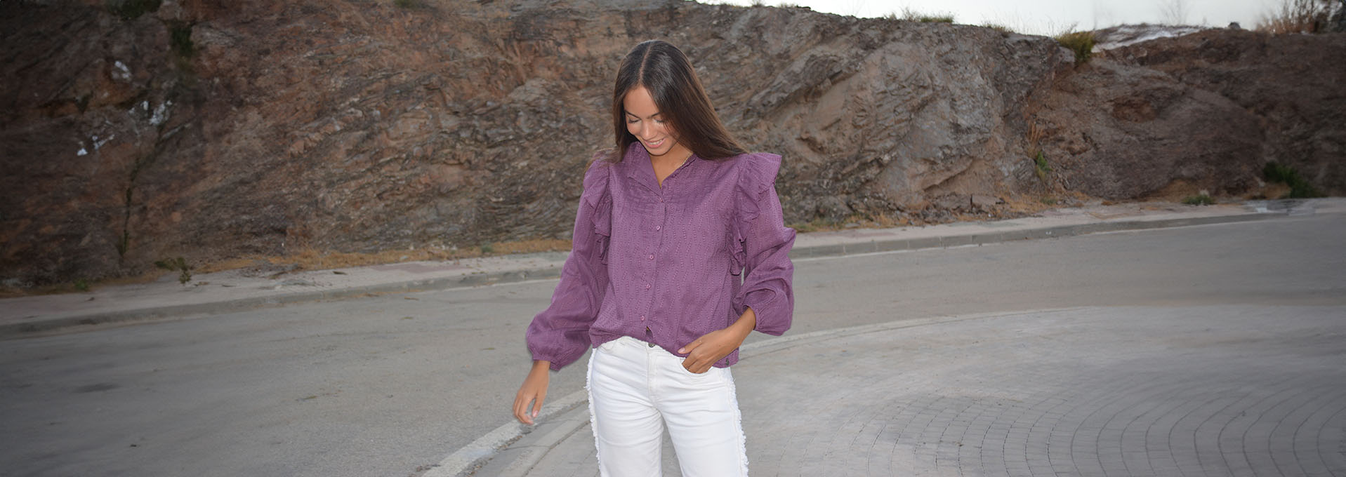 chica posando delante de una pared con una camisa antracita con rayas de lurex plateadas y tejano azul claro