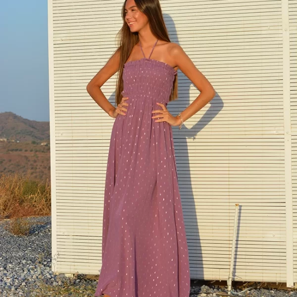 chica sonriendo con un vestido largo rosa con lunares de hilo plateado. cuerpo fruncido de nido de abeja y cordón en cuello para anudar