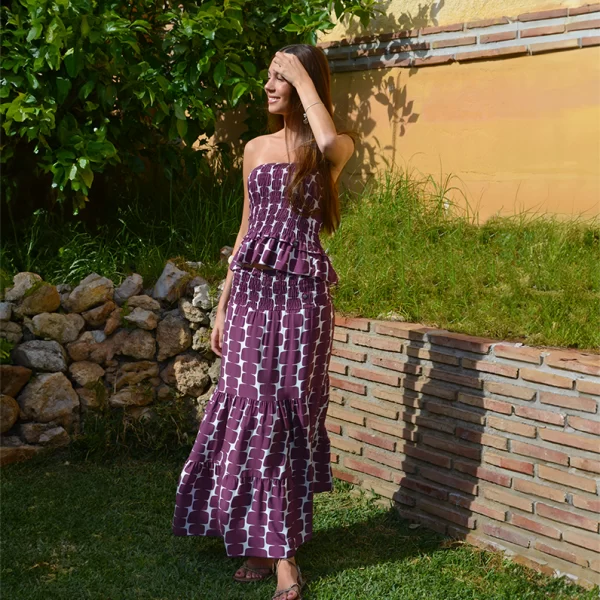 chica en un jardin con un Conjunto de top fruncido palabra de honor y falda estampado en blanco y berenjena.