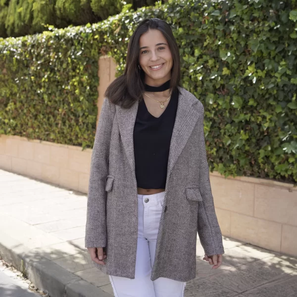 chica sonriendo con una abrigo de espiga largo con 2 botones frontales para el cierre