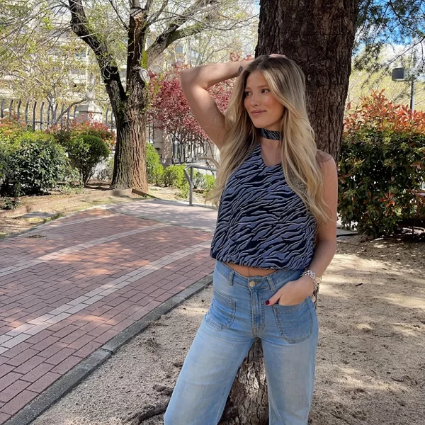 chica psando con una mano en el pelo con una blusa estampado cebra y un tejano azul