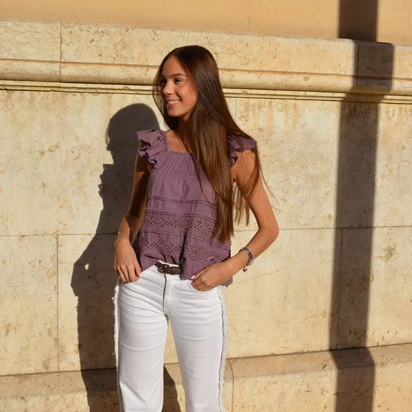 chica posando con una blusa top rosa viejo y pantalón blanco