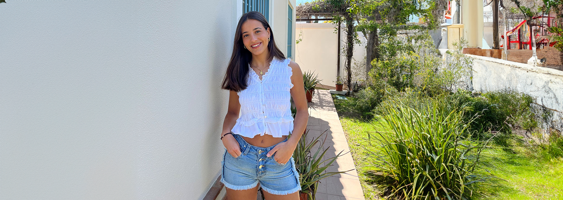 chica posando delante de una pared con una camisa antracita con rayas de lurex plateadas y tejano azul claro
