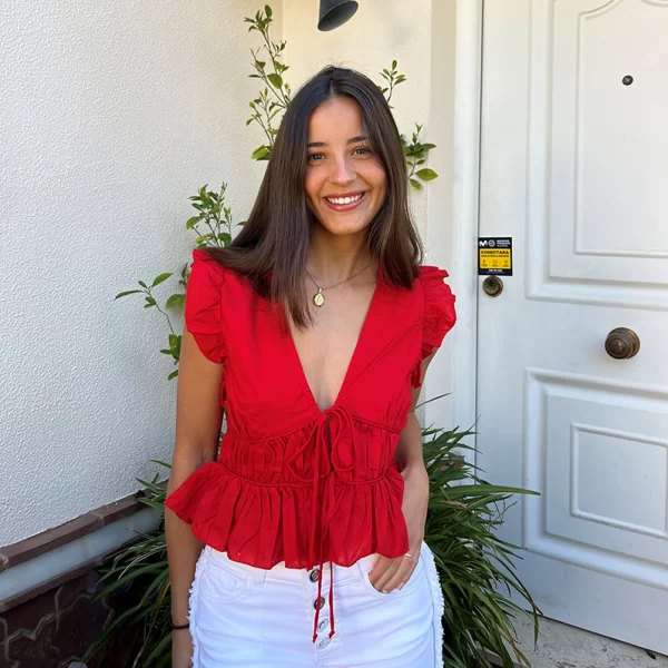 chica posando con una blusa roja y short blanco
