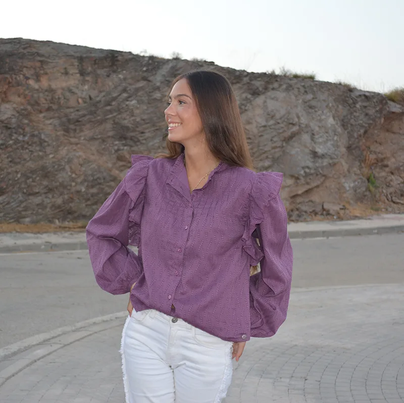 chica con una blusa berenjena y pantalón blanco en una carretera vacía