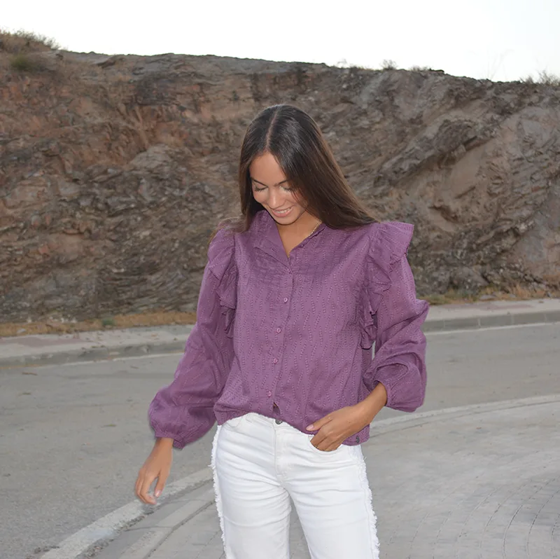 chica con una blusa berenjena y pantalón blanco en una carretera vacía