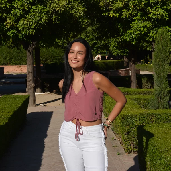 chica posando con una blusa top rosa viejo con nudo frontal para ajustar y pantalón blanco