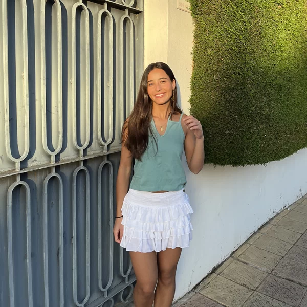 chica posando con un top verde de tirantes dobles y Falda pantalón blanca con cuatro volantes, fruncido con gomas elásticas en cintura y short interior de punto liso a tono.