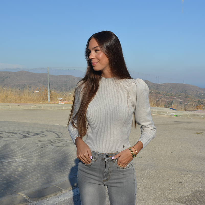 chica sonriendo con un jersey de canalé gris y tejano gris