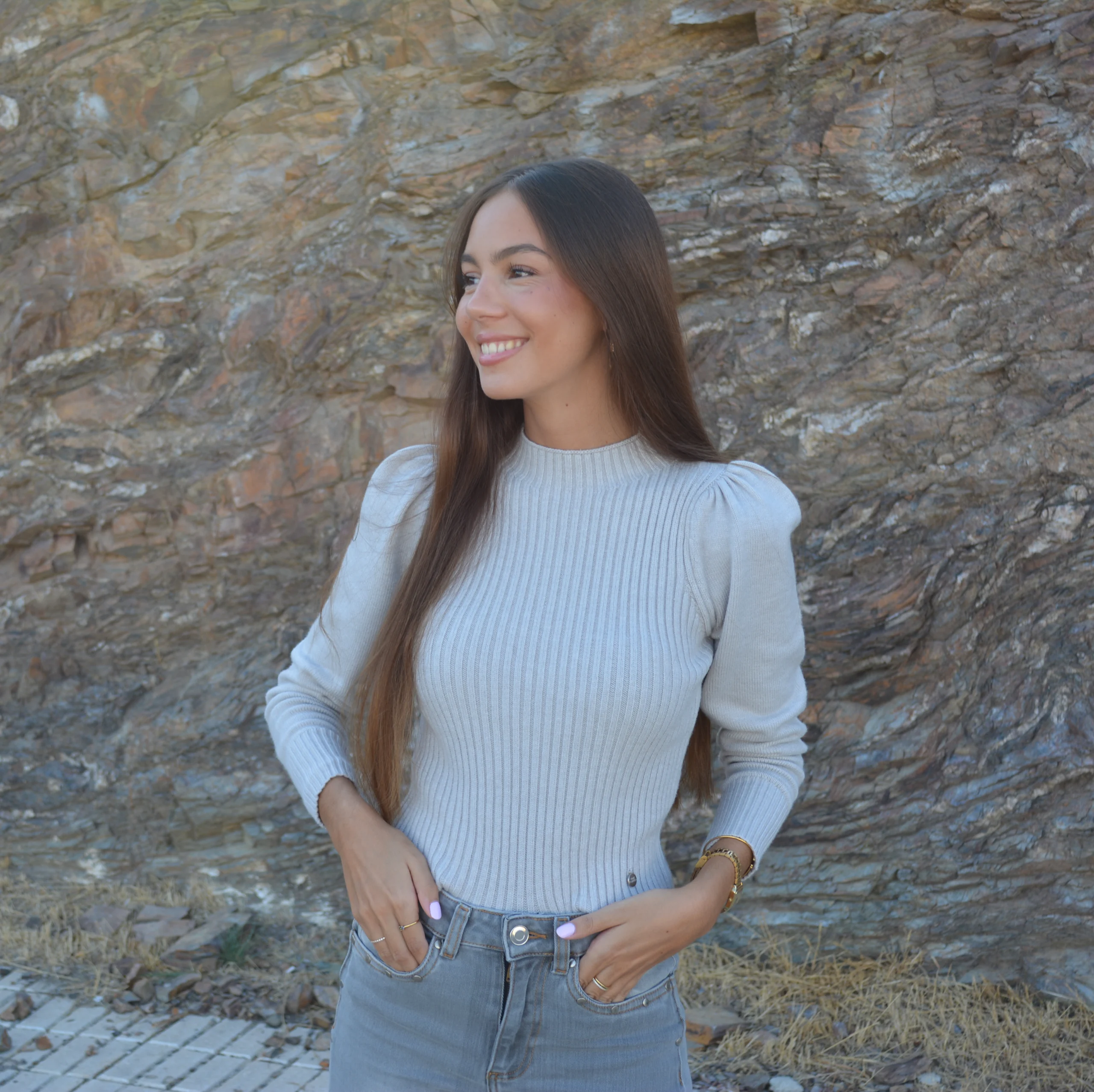 chica sonriendo con un jersey de canalé gris y tejano gris
