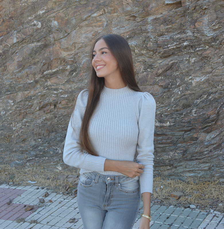 chica sonriendo con un jersey de canalé gris y tejano gris