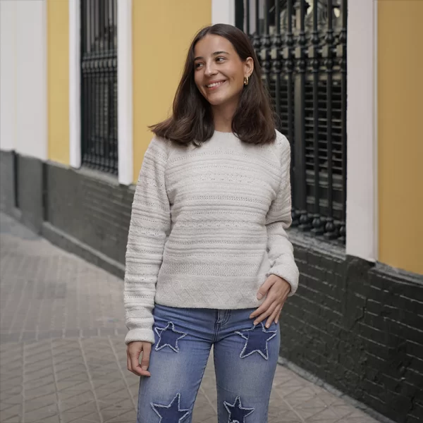 chica posando con un jersey fantasía en gris claro y pantalón tejano azul con apliques de estrellas a sobre tono