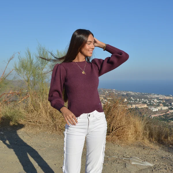 chica con un tejano blanco y un jersey berenjena de manga abullonado de tricotosa