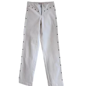 Pantalón tejano blanco 2 bolsillos con pieza en cintura, cremallera frontal, tachuelas de estrella en los laterales, frontal y dos bolsillos traseros. 98%Algodón, 2%Elastán