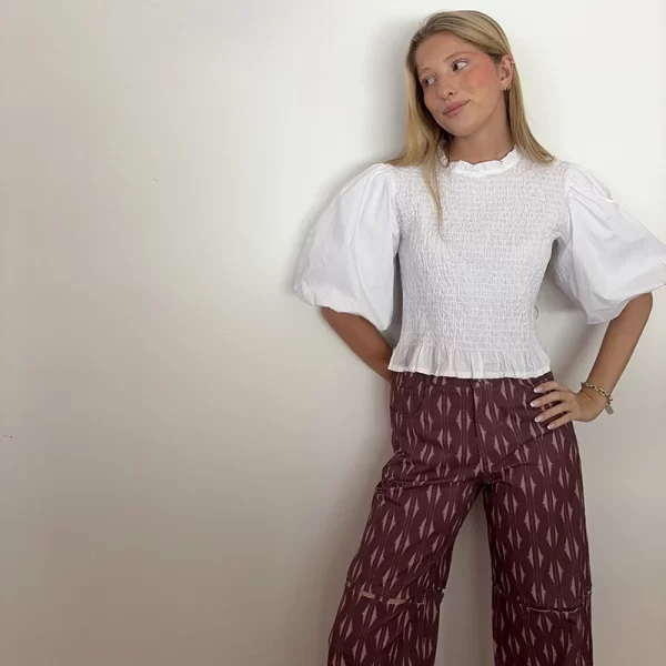 chica rubia posando con una blusa blanca con manga abullonada