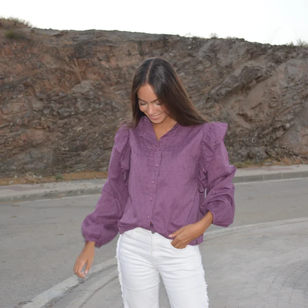 chica con una blusa berenjena y pantalón blanco en una carretera vacía