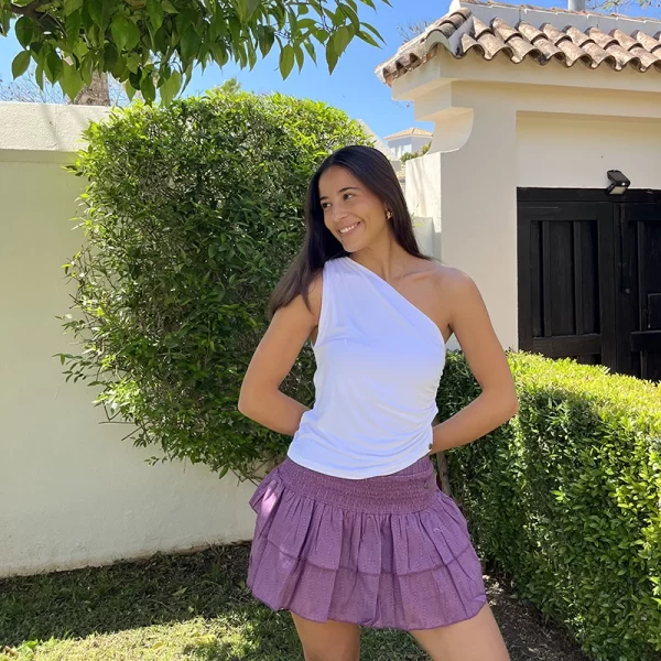 chica posando en jardin con un top asimétrico blanco