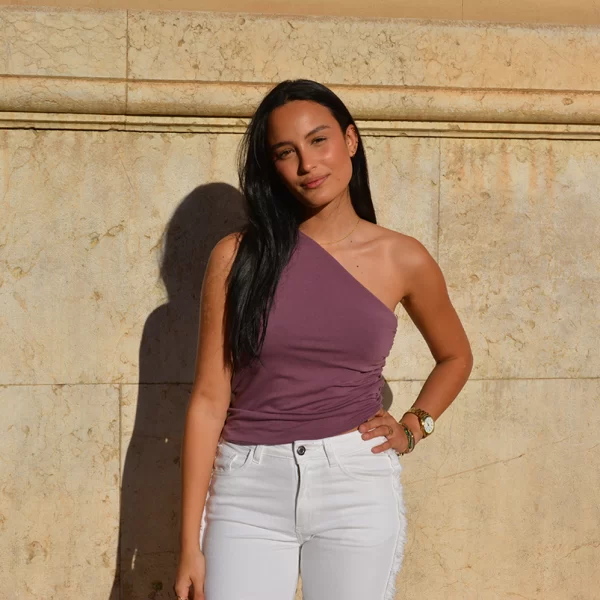 chica posando con una blusa top rosa viejo asimétrico y pantalón blanco