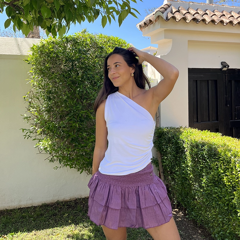 chica posando en jardin con un top asimétrico blanco