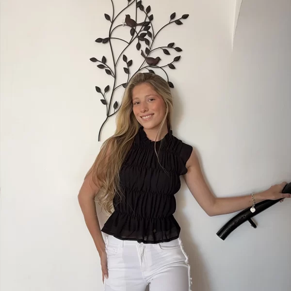 chica posandpo con una blusa sin mangas de color negro y rizada