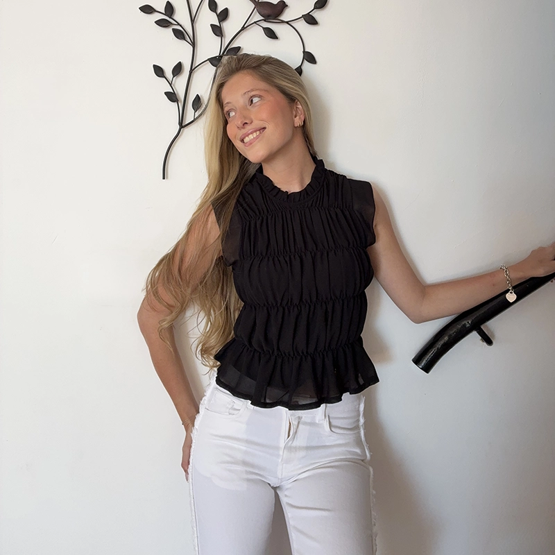 chica posando delante del mar con una camiseta blanca con un estampado de alas en color plateado en la espalda