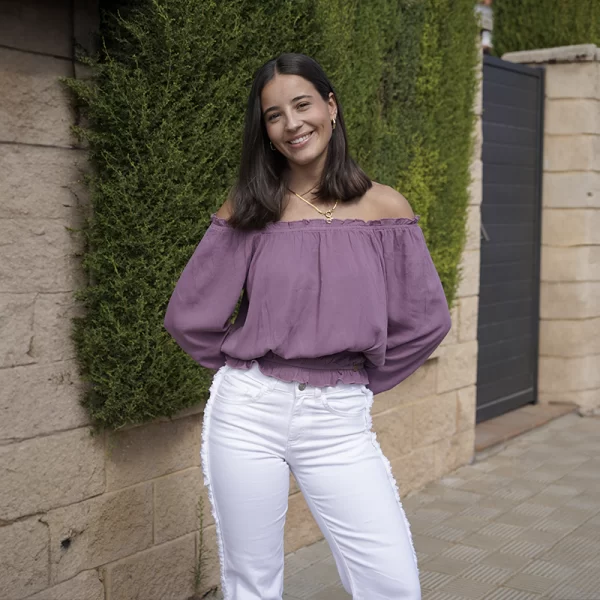 chica posando con un topo de manga larga con cuello barco de gomas elásticas y pantalón blanco