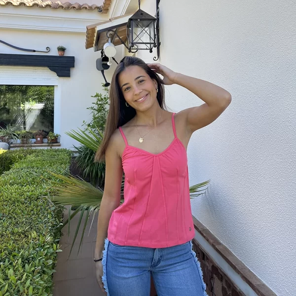 chica posando en jardin con una camiseta de tirantes en color coral