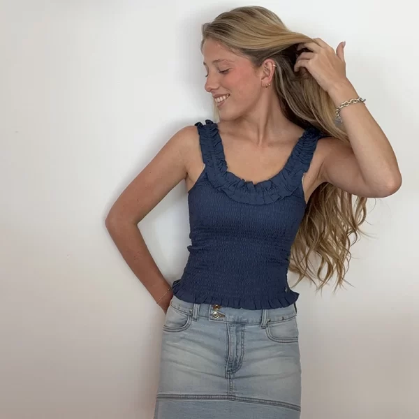 chica rubia posando con un top azul fruncido