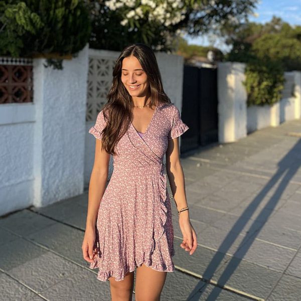 chica sonriendo con un vestido corto crudo rosa de florecillas blancas con manga corta