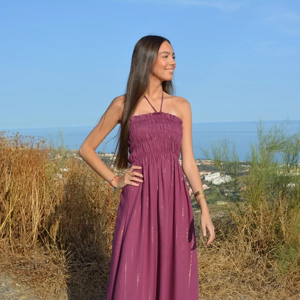chica posando con un vestido largo con cordon en cuello para anudad y parte del pecho fruncido en color berenjena con hilo de lúrex en dorado